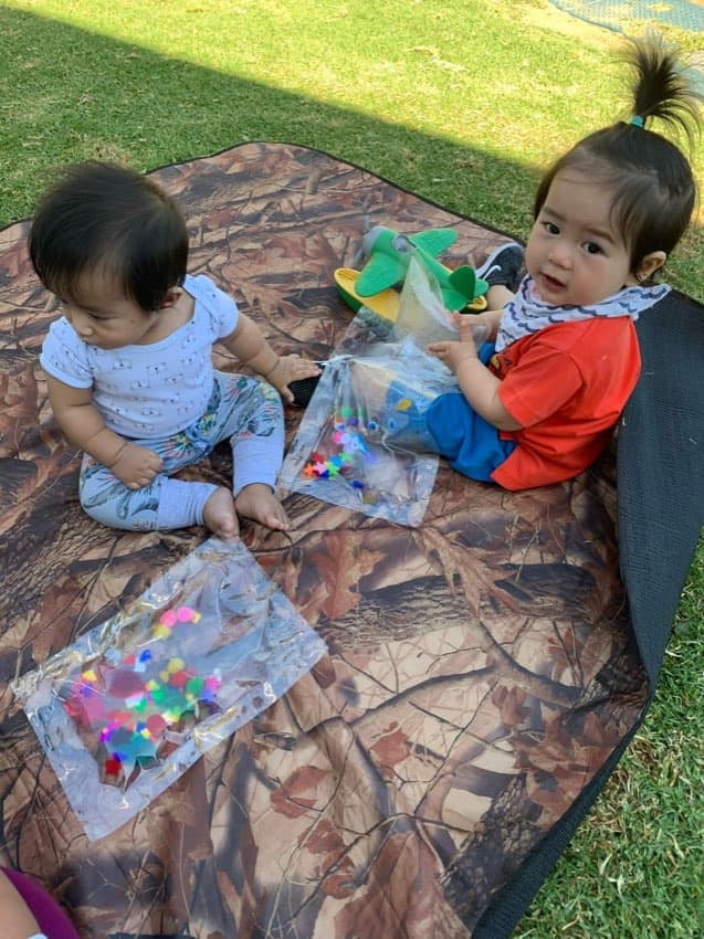 Infants exploring toys during outdoor play